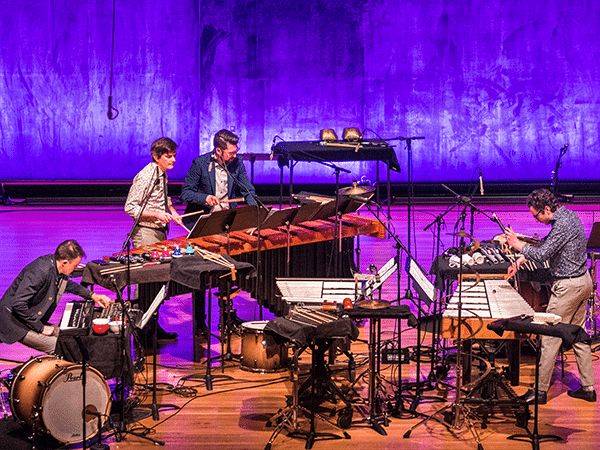 Third Coast Percussion, a percussion ensemble, plays on stage with with assortment of percussion instruments.
